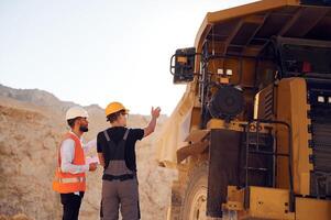 Looking at big haul truck... Two men in uniform are working together in the quarry photo