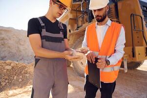 Checking ,rock, that is in the hands. Two men in uniform are working together in the quarry photo