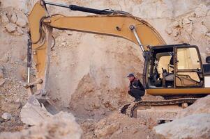 Middle, aged man is with excavator in the quarry at daytime photo