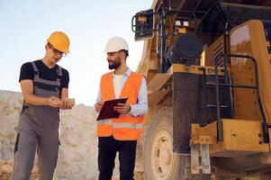 Holding and showing, rock that is in the hand. Two men in uniform are working together in the quarry photo