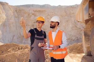 Holding and showing rock that is in the hand.. Two men in uniform are working together in the quarry photo