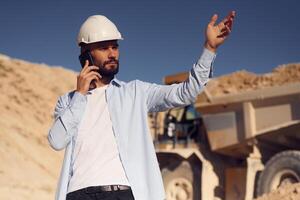 Talking by phone. Man in uniform is working in the quarry at daytime photo
