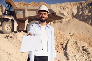 Document to, fulfill. Man in uniform is working in the quarry at daytime photo