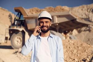 Engineer is with the phone. Man, in uniform is working in the quarry at daytime photo