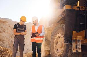Holding, and showing rock that is in the hand. Two men in uniform are working together in the quarry photo