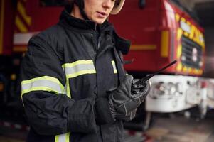 Using ,radio transmitter. Woman firefighter in uniform is at work in department photo
