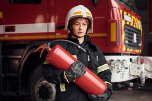 Fire extinguisher in in the hands of woman that is in uniform at work in department photo