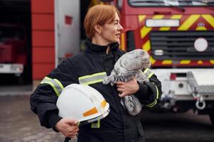 Conception, of savior. Holding ,cat in hands. Woman firefighter in uniform is at work in department photo