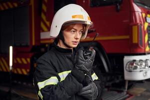 Talking by using radio transmitter. Woman firefighter in uniform is at work in department photo