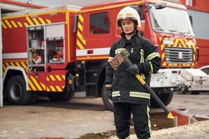 In, uniform with axe in hands. Woman firefighter is at work in department photo