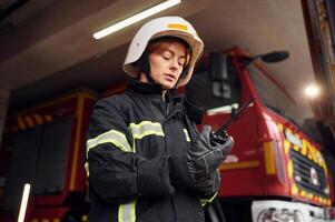 Using, radio transmitter. Woman firefighter in uniform is at work in department photo