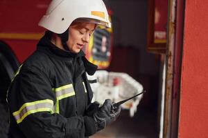 Using radio transmitter. .Woman firefighter in uniform is at work in department photo