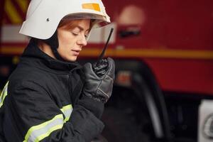 Using radio transmitter. Woman firefighter, in uniform is at work in department photo