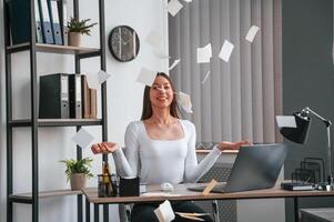 Throwing stickers up into air.. Young beautiful woman in white clothes is in the office photo