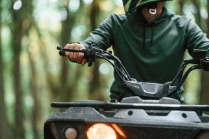 Front view.. ATV driver is in the forest, having a ride at daytime photo