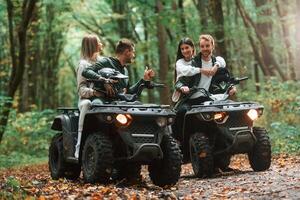 Man, showing thumb up. Two couples on a quad bike in the forest during the day photo