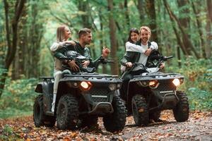 Smiling ,and having fun. Two couples on a quad bike in the forest during the day photo