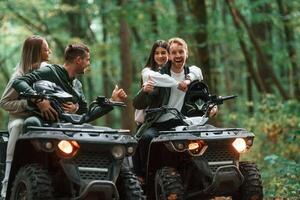 Smiling and, having fun. Two couples on a quad bike in the forest during the day photo