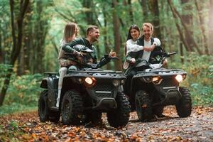 Smiling ,and ,having fun. Two couples on a quad bike in the forest during the day photo