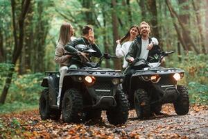 Smiling, and having fun. Two couples on a quad bike in the forest during the day photo