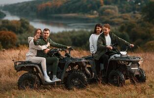 Making ,a selfie by smartphone. Two, young couples with quad bikes is together on the field photo