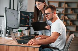 Analyzing ,information from computer screens. Two stock brokers is working together in the office with finances photo