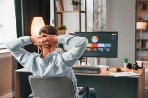 Designer is, sitting, by the computer and using graphics tablet with stylus photo