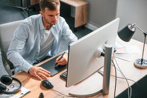 Top view. Designer is, sitting by the computer and using graphics tablet with stylus photo