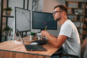 Laptop is on the table. Young stock, broker is working in the office by using computer photo