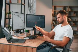 Laptop is on the table.. Young stock broker is working in the office by using computer photo