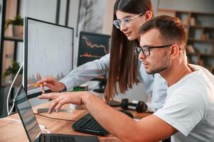 Analyzing, information from computer screens. Two stock brokers is working together in the office with finances photo