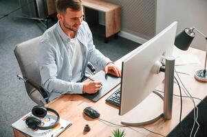 Top, view. Designer is sitting by the computer and using graphics tablet with stylus photo