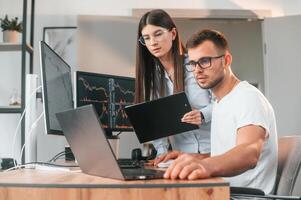 Analyzing information from ,computer screens. Two stock brokers is working together in the office with finances photo