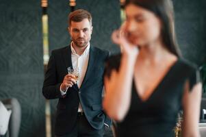Man ,in black suit is angry at woman that is standing and crying photo