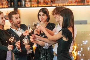 Having fun. Group ,of people ,in beautiful elegant clothes are celebrating New Year indoors together photo