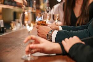 Close, up view of hands with glasses. Group of people in beautiful elegant clothes are celebrating New Year indoors together photo