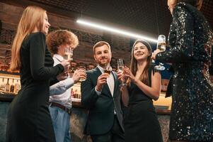 Standing, talking, holding glasses. Group ,of people in, beautiful elegant clothes are celebrating New Year indoors together photo