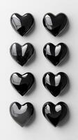Collection of glossy black heart-shaped stones arranged in a grid on a light surface photo