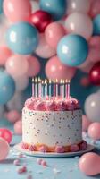 Birthday cake with colorful candles surrounded by pink and blue balloons celebrating a joyful occasion photo