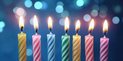 Colorful birthday candles burning brightly against a shimmering blue background during a celebration photo