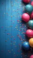 Colorful balloons and confetti create a festive atmosphere on a blue wooden surface for a celebration or party photo