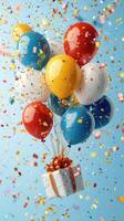 Colorful balloons and confetti celebrate a festive event with a wrapped gift against a cheerful blue background photo