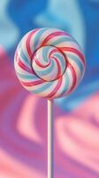 Colorful swirled lollipop with blue and pink stripes against a vibrant background photo