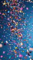 Colorful confetti falling against a vibrant blue background during a festive celebration photo