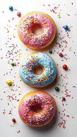 Vibrant donuts with colorful frosting and sprinkles adorned with candy on a white surface photo
