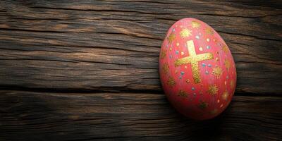 Beautifully decorated Easter egg resting on a rustic wooden table with a golden cross and colorful designs photo