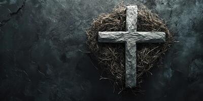 Cross made of stone rests on a dark surface surrounded by straw representing faith and spirituality in a somber setting photo