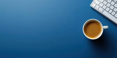 Coffee cup beside a keyboard on a blue desk during a quiet workday photo