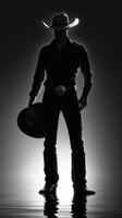Cowboy silhouette standing in water at sunset with hat and belt buckle in a striking black and white composition photo
