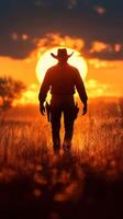 Cowboy silhouette walking through grass at sunset in the open countryside photo